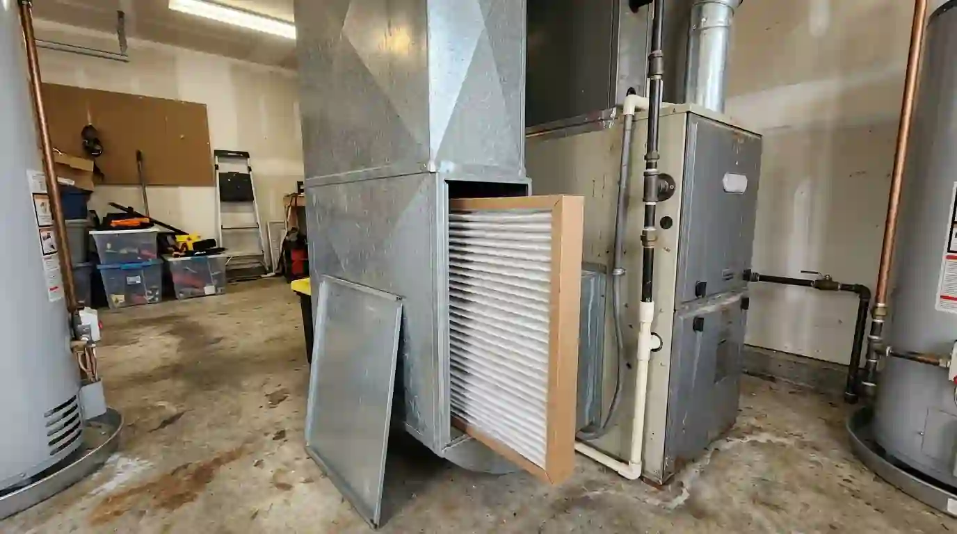 Thick media filter pulled from its cabinet beside a furnace